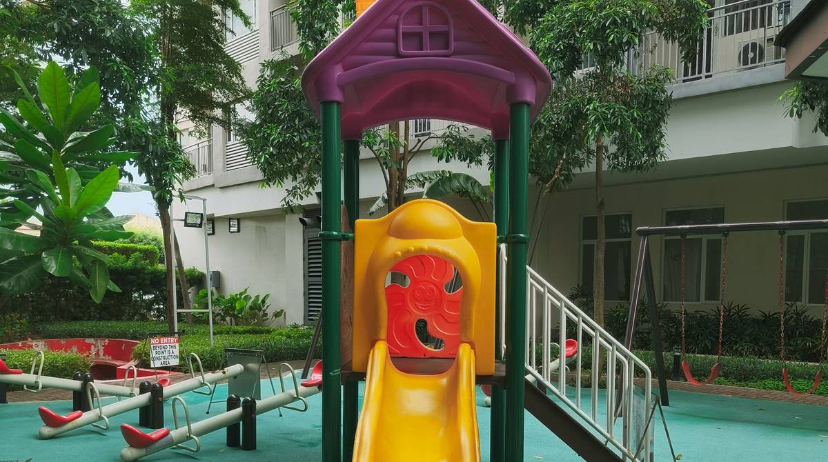Playground infantil de condomínio com escorregador, gangorra e balanços de plástico colorido sobre piso de amortecimento emborrachado