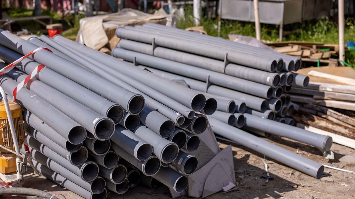 Pilha de tubos de PVC cinza empilhados em canteiro de obras, material plástico usado em reparo por solda