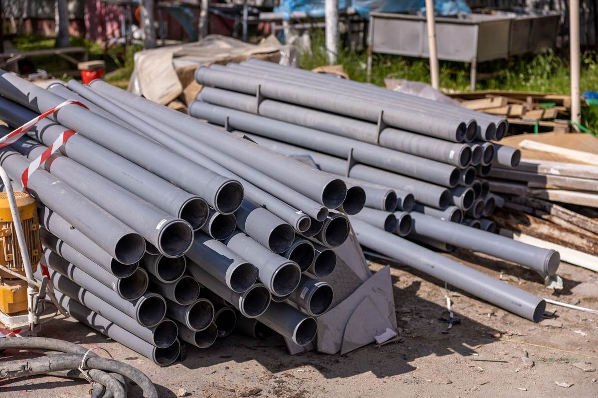 Pilha de tubos de PVC cinza empilhados em canteiro de obra